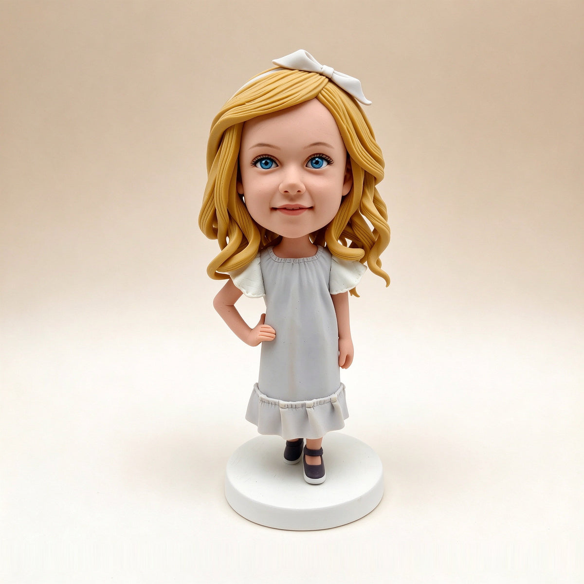 Handmade polymer clay bobblehead keepsake figurine of a girl with blonde hair and a white bow