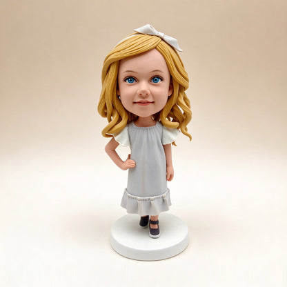 Handmade polymer clay bobblehead keepsake figurine of a girl with blonde hair and a white bow