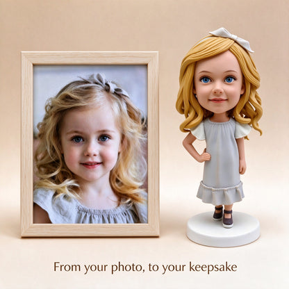 Custom handmade polymer clay bobblehead figurine shown next to the original photo of the girl it was made from